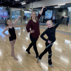 Two young girls and an instructor holding a dance pose